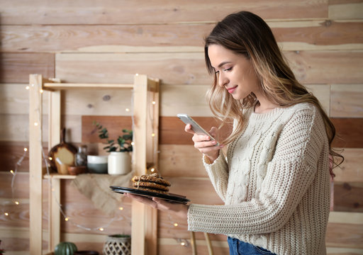 Female food photographer with mobile phone taking picture of tasty cookies in home studio