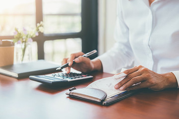 Woman with bills and calculator. Woman using calculator to calculate bills at the table in office. Calculation of costs.