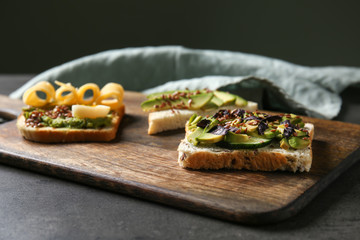 Different tasty sandwiches with avocado on wooden board