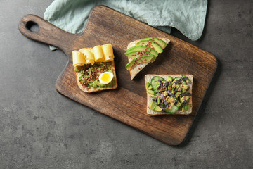 Different tasty sandwiches with avocado on grey table