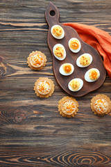 Tasty deviled eggs with tartlets on wooden table