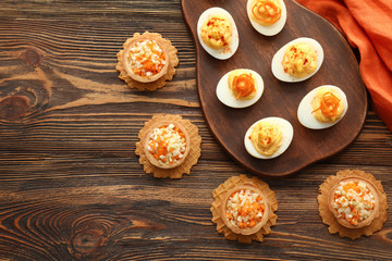 Tasty deviled eggs with tartlets on wooden table