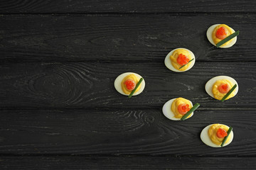 Tasty deviled eggs on dark wooden table
