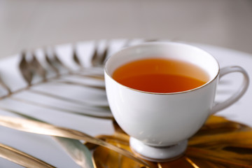 Cup of tea with tropical leaves on table, closeup