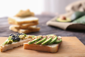 Tasty avocado sandwiches on wooden board, closeup