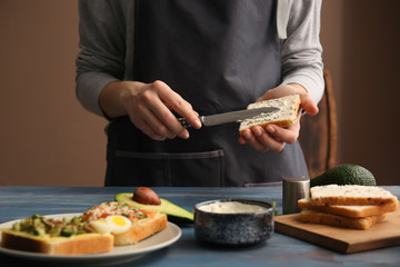 Woman preparing tasty sandwich with avocado in kitchen