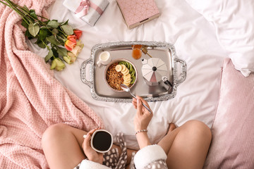 Young woman having breakfast on bed