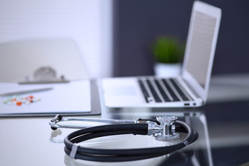 Stethoscope, prescription medical form lying on glass table with laptop computer. Medicine or pharmacy concept. Medical tools at doctor working table