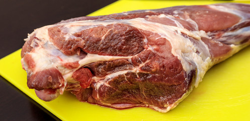 Raw meat on a bright color cutting board, on a dark background