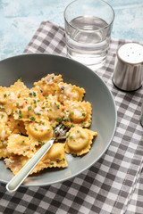 Plate with tasty ravioli on table