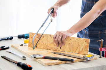 Carpenter working carefully looking at the plans work in carpentry. He is successful entrepreneur at his workplace. hammering a nail Supports On Building Site work with cutter.