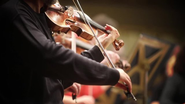 Close up footage of a person performing on a violin during a concert.
