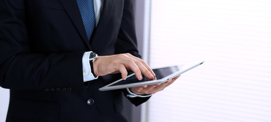 Unknown businessman using digital tablet in office background. Business concept