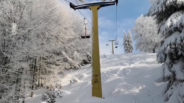 Footage of a chairlift on a mountain, on a snowy winter day.