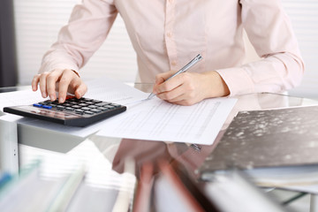 Unknown bookkeeper woman or financial inspector  making report, calculating or checking balance, close-up. Business portrait. Audit or tax concepts