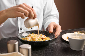 Male chef preparing for serving tasty ravioli on table
