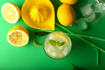 Glass of tasty cold lemonade on color background