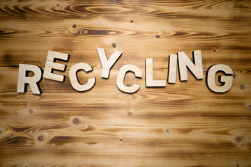 RECYCLING word made with building blocks on wooden board.