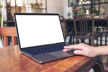 Closeup image of hand using and touching on mockup laptop touchpad on wooden table