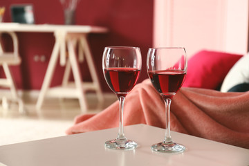 Glasses of wine on light table in living room