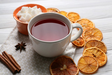 Cup of hot tea with orange slices on wooden table