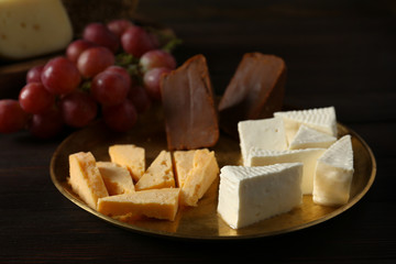 Plate with assortment of tasty cheese on wooden table