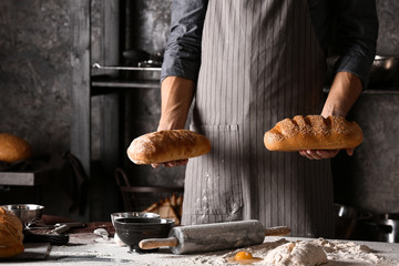 Young man with freshly baked bread in kitchen