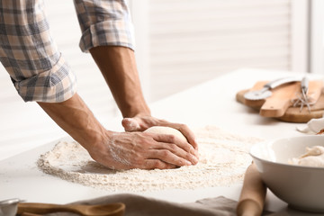 Young man preparing dough for bread in kitchen