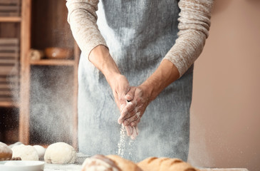 Young man preparing dough for bread in kitchen