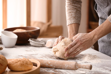 Young man preparing dough for bread in kitchen - obrazy, fototapety, plakaty