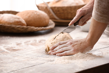 Young man preparing dough for bread in kitchen, closeup