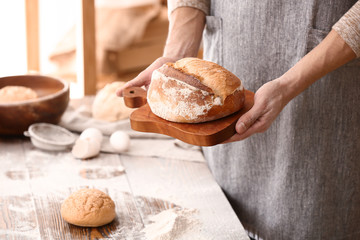 Young man with freshly baked bread in kitchen
