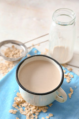 Mug of tasty oat milk on white table
