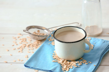 Mug of tasty oat milk on white table