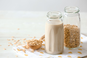 Glass bottle of tasty oat milk on light table