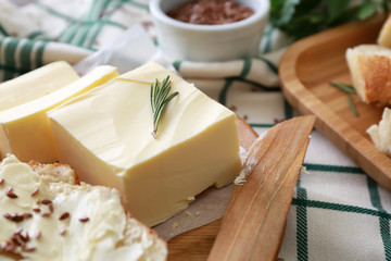 Wooden board with tasty butter and bread on table