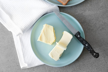 Plate with tasty butter on grey table