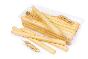 Breadsticks with sesame seeds and wheat ears on white background