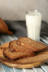 Wooden plate with slices on tasty fresh bread on table