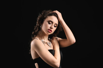 Fototapeta premium Young woman with beautiful jewelry on dark background