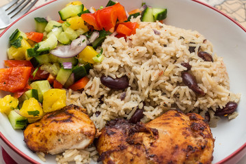 Jerk chicken, rice and peas with a side of fresh homemade salsa in a bowl