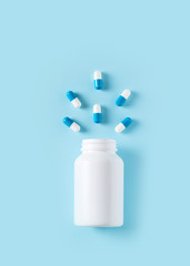 Some capsules and bottle on blue background. Healthcare concept with pills