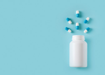 Some capsules and bottle on blue background. Healthcare concept with pills