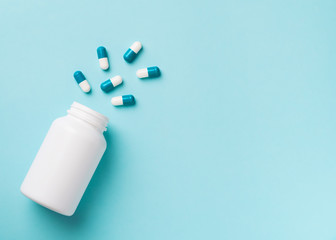 Some capsules and bottle on blue background. Healthcare concept with pills