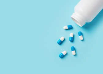 Some capsules and bottle on blue background. Healthcare concept with pills