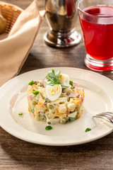 Traditional Russian salad Olivier with boiled egg on top on on wooden table