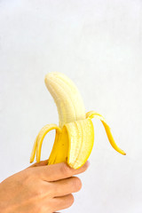 Hand held half peeled banana isolated on a white background