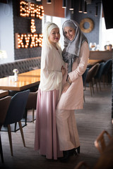 Two young muslim women standing in the cafe