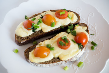 Multigrain toast bread with melt gouda or kaseri cheese and small tomatoes and green onion on top 