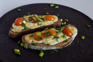 Multigrain toast bread with melt gouda or kaseri cheese and small tomatoes and green onion on top 